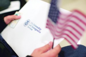 A man holds a U.S. flag while receiving his proof of U.S. citizenship during a ceremony in San Francisco